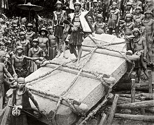 Nias men carrying a stone for construction for the deceased ruler Saunigeho of Bawömataluo around 1915.