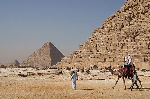 Tourists riding an Arabian camel in front of Pyramid of Khafre. The Giza Necropolis is one of Egypt's main tourist attractions.